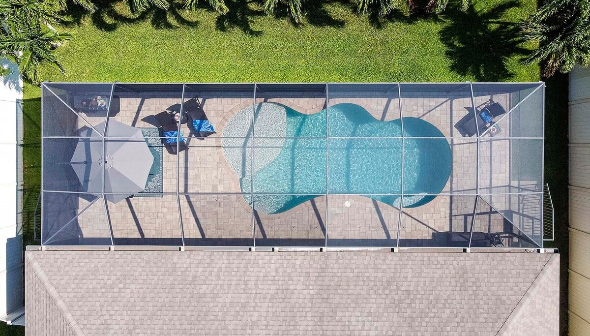 Überdachte Lanai mit Outdoor-Dining, Außenküche und Blick auf den beheizten Salzwasser-Pool.