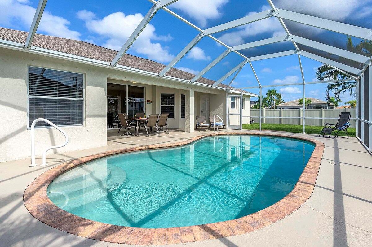 Überdachte Veranda mit Sitzbereich und Blick in den eingezäunten Garten.