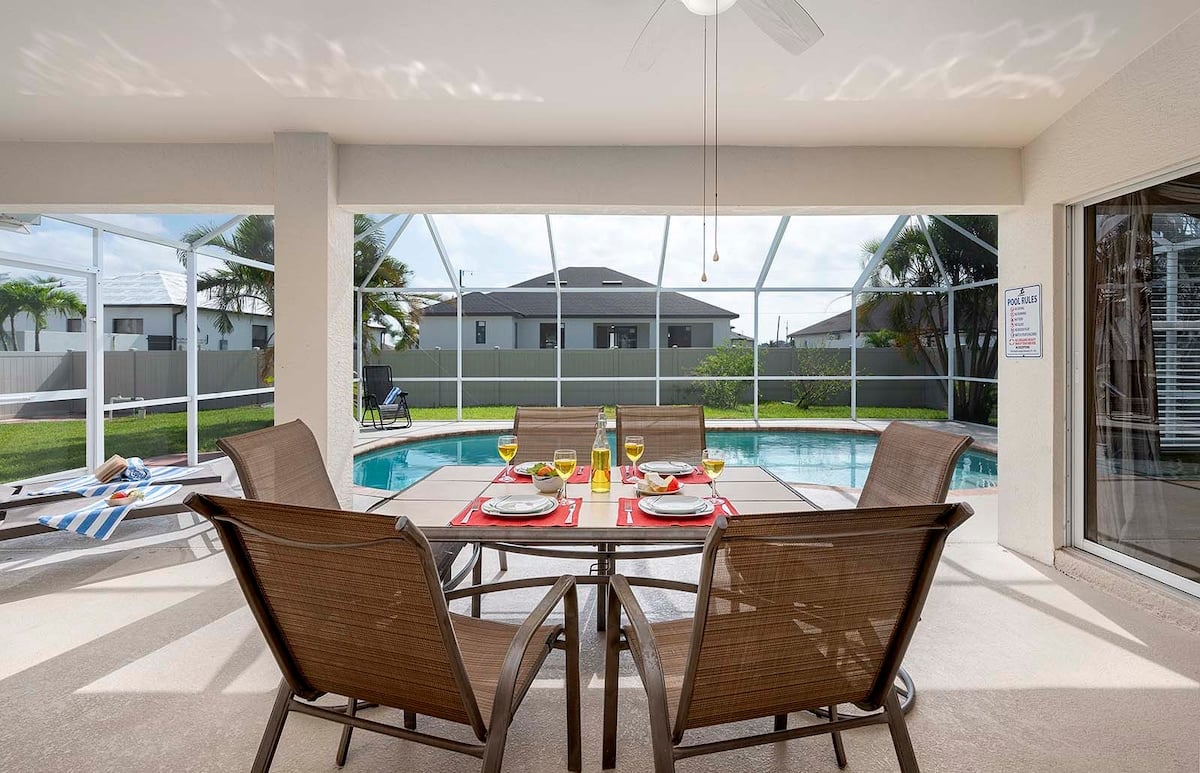 Überdachte Veranda mit Sitzbereich und Blick in den eingezäunten Garten.