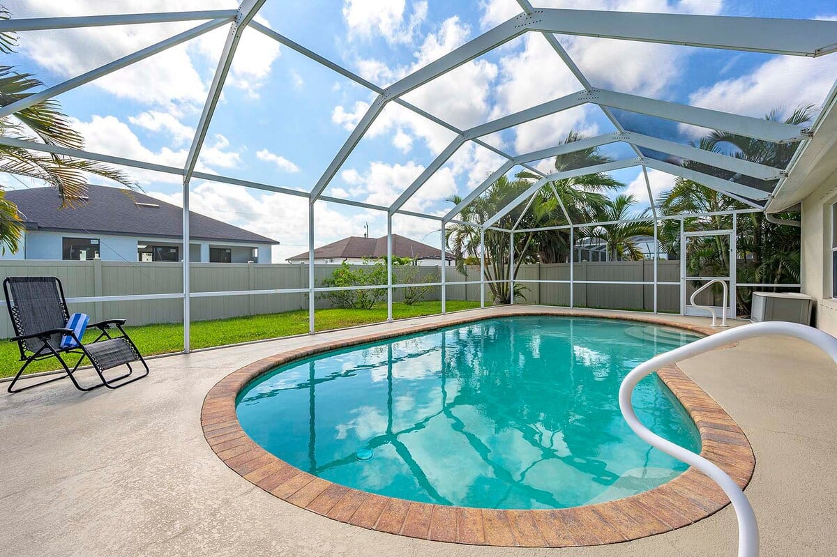 Überdachte Veranda mit Sitzbereich und Blick in den eingezäunten Garten.