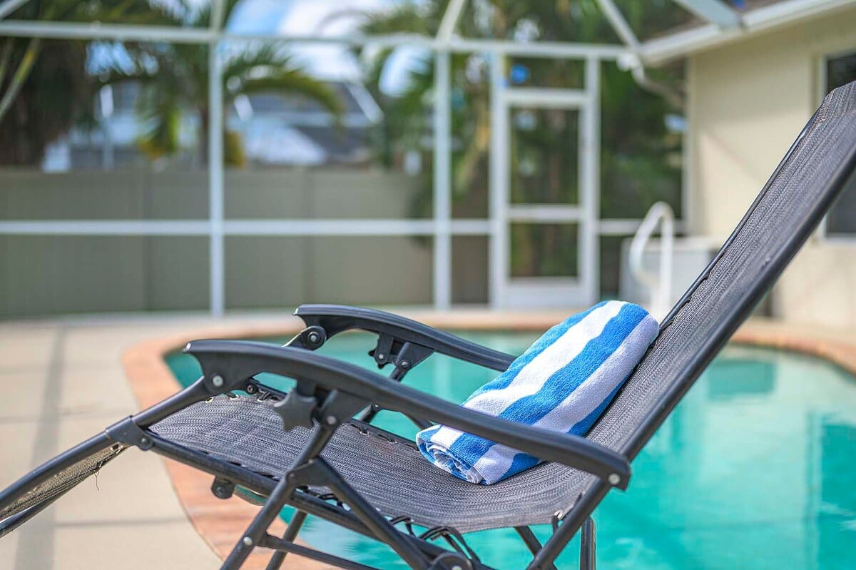 Überdachte Veranda mit Sitzbereich und Blick in den eingezäunten Garten.