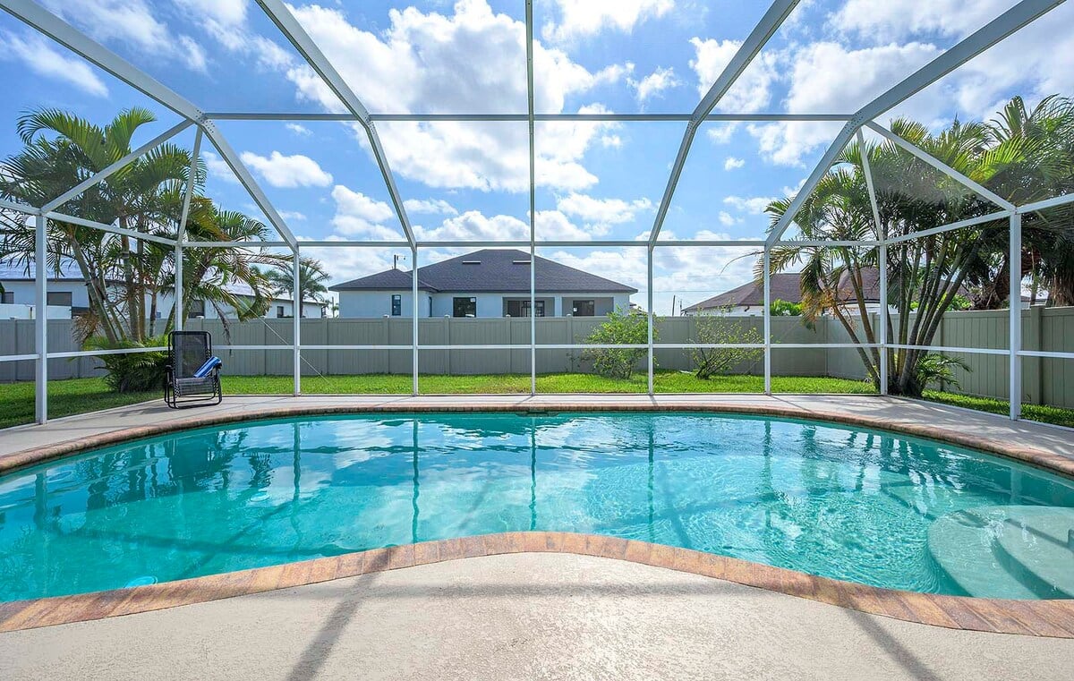 Überdachte Veranda mit Sitzbereich und Blick in den eingezäunten Garten.
