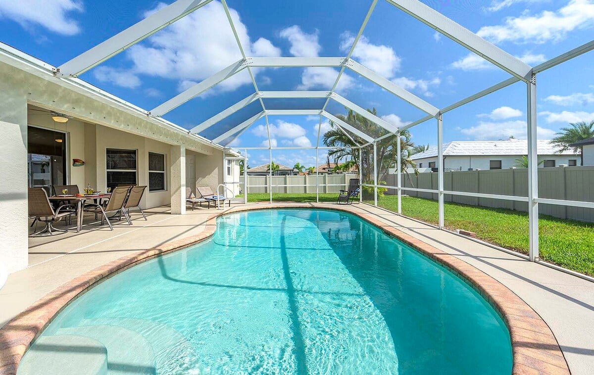 Überdachte Veranda mit Sitzbereich und Blick in den eingezäunten Garten.