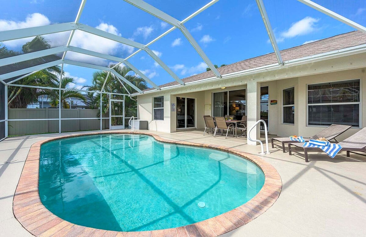 Überdachte Veranda mit Sitzbereich und Blick in den eingezäunten Garten.