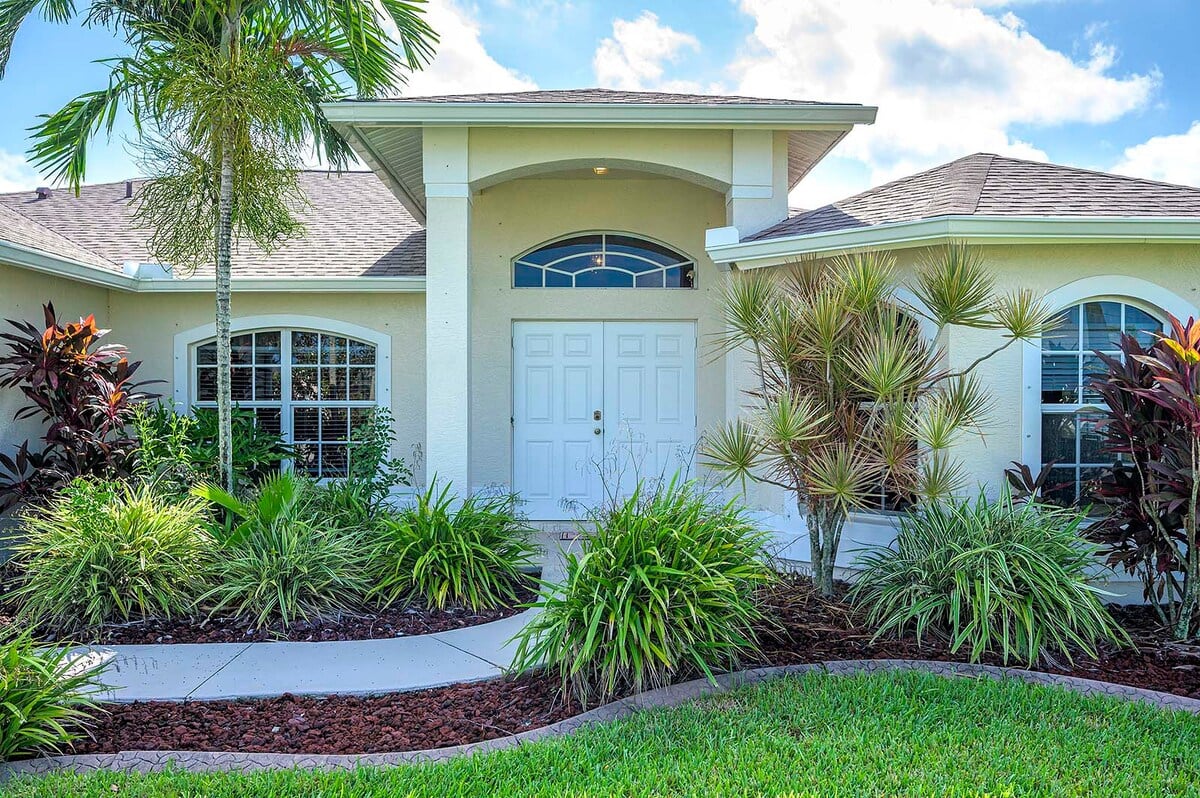 Überdachte Veranda mit Sitzbereich und Blick in den eingezäunten Garten.