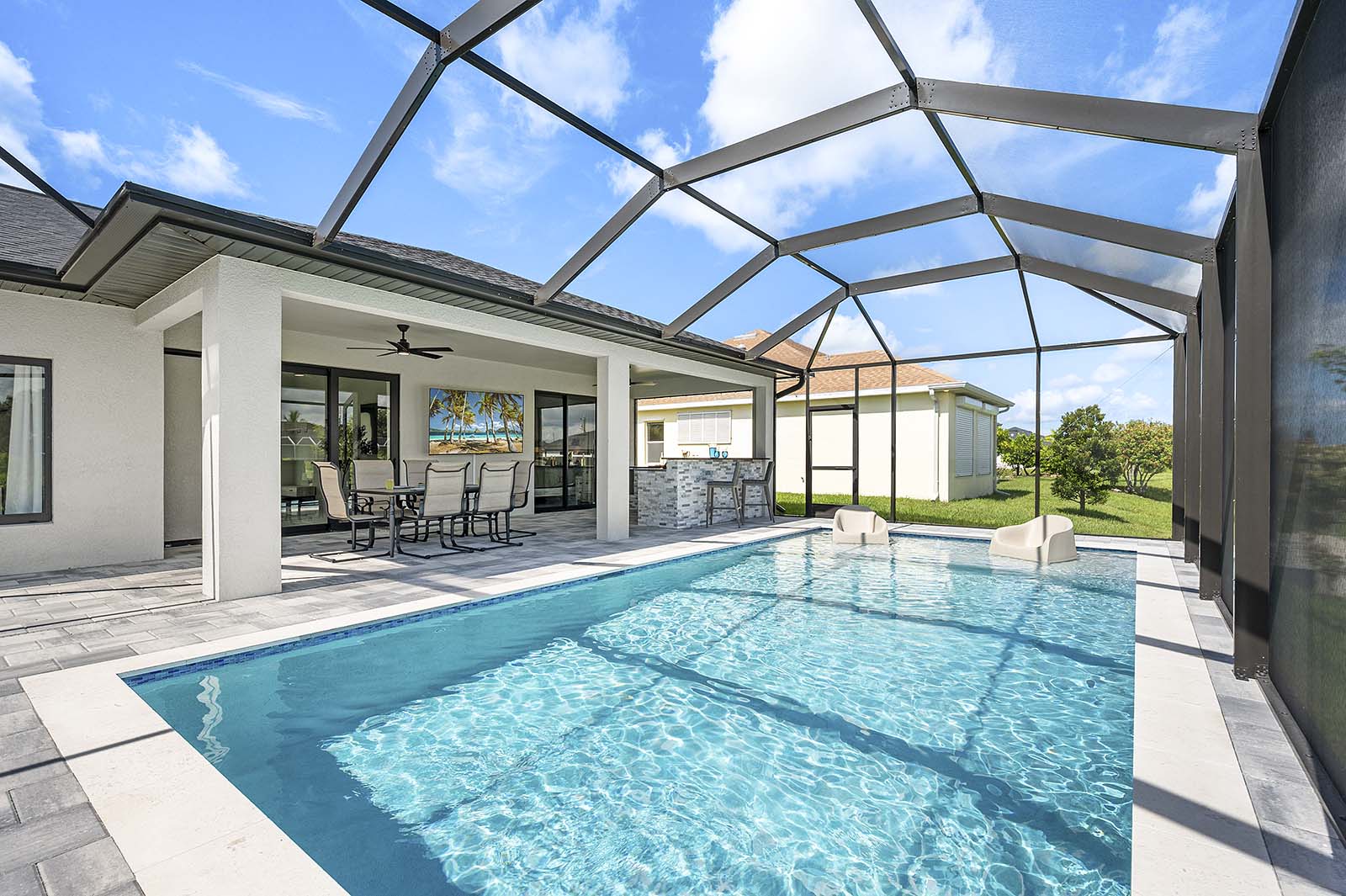 Poolbereich mit Outdoor-Küche, Grill und TV unter der überdachten Lanai.