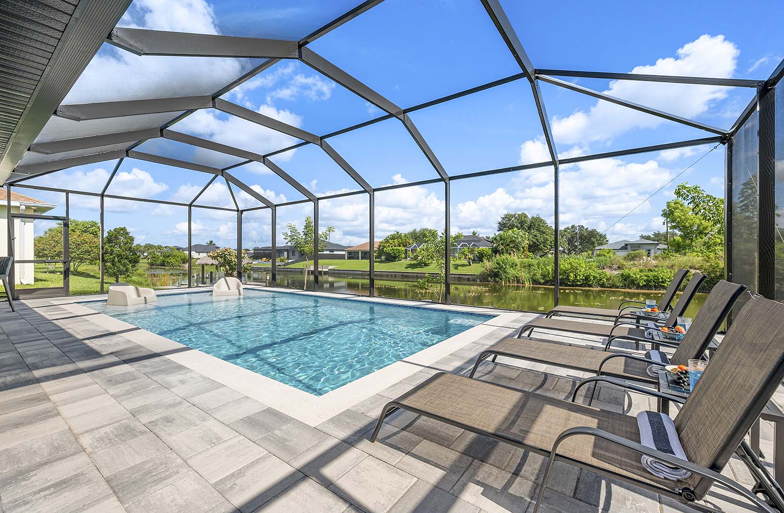 Großer Poolbereich mit Sonnenliegen, Outdoor-Küche und TV auf der Lanai.