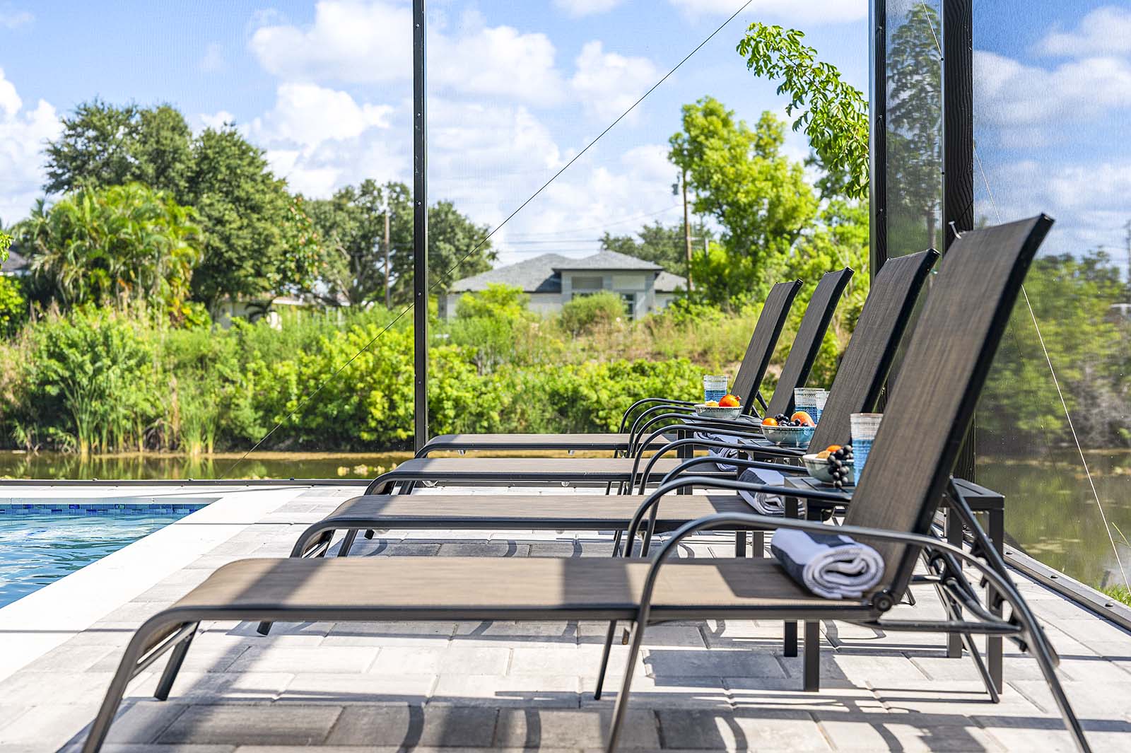 Poolbereich mit Outdoor-Küche, Grill und TV unter der überdachten Lanai.