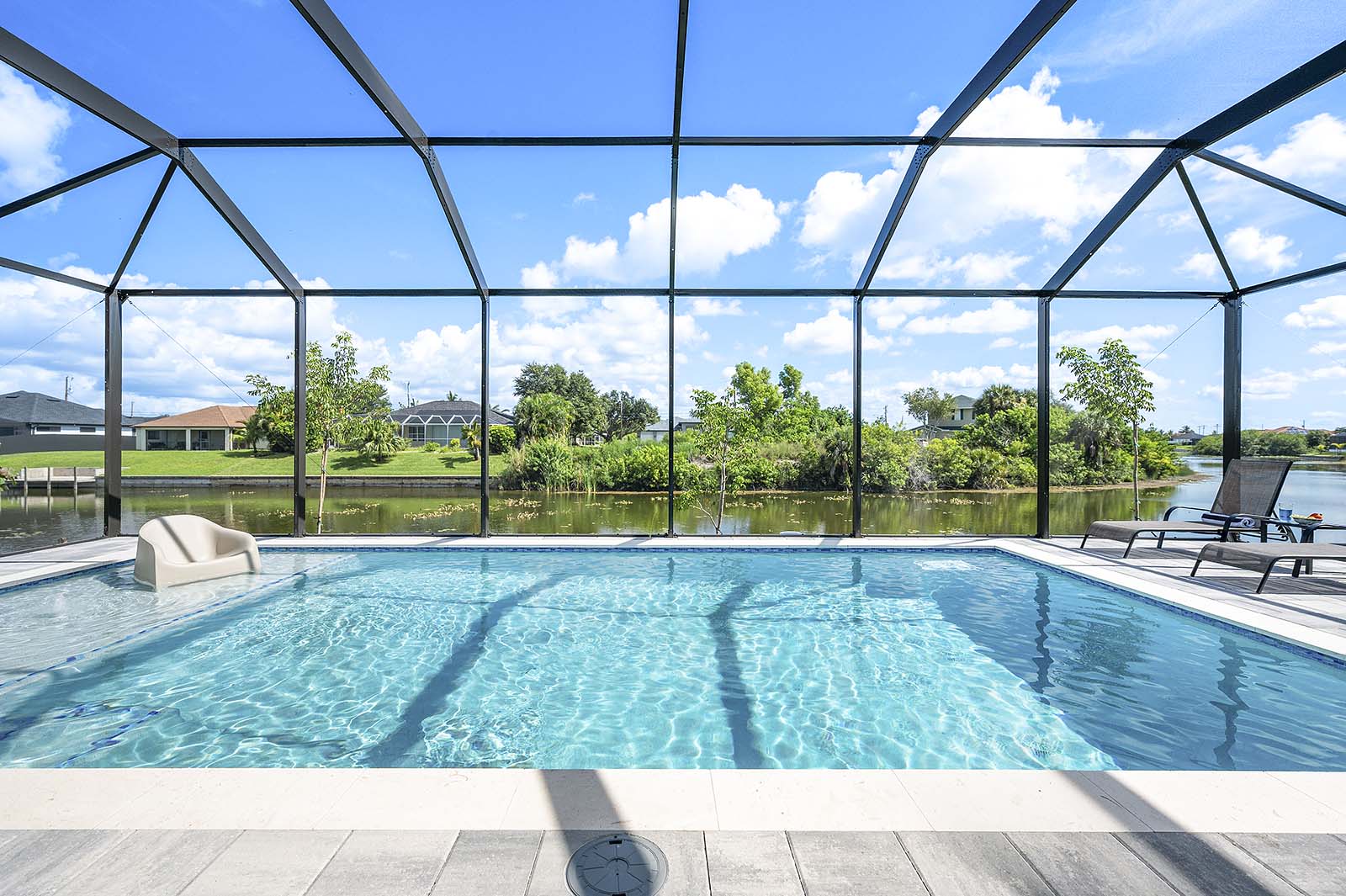 Großer Pool mit Sonnenliegen und überdachter Lanai am Kanal.