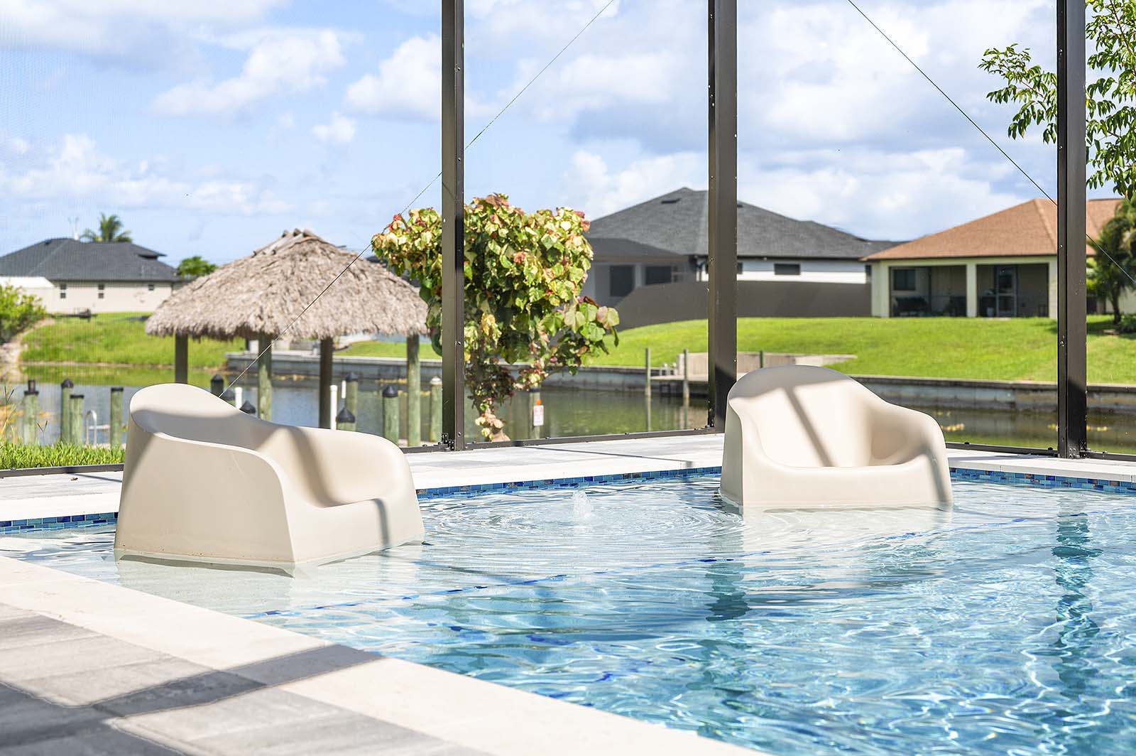 Poolbereich mit Outdoor-Küche, Grill und TV unter überdachter Lanai.