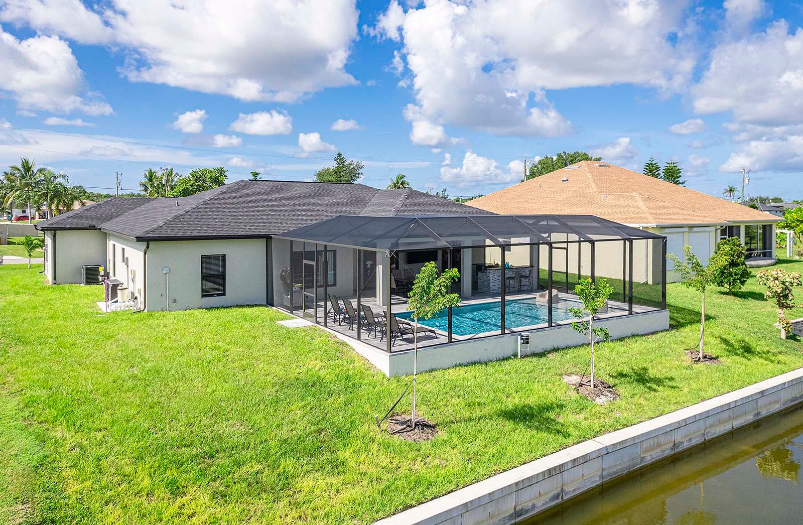 Poolbereich mit Outdoor-Küche, Grill und TV unter überdachter Lanai.