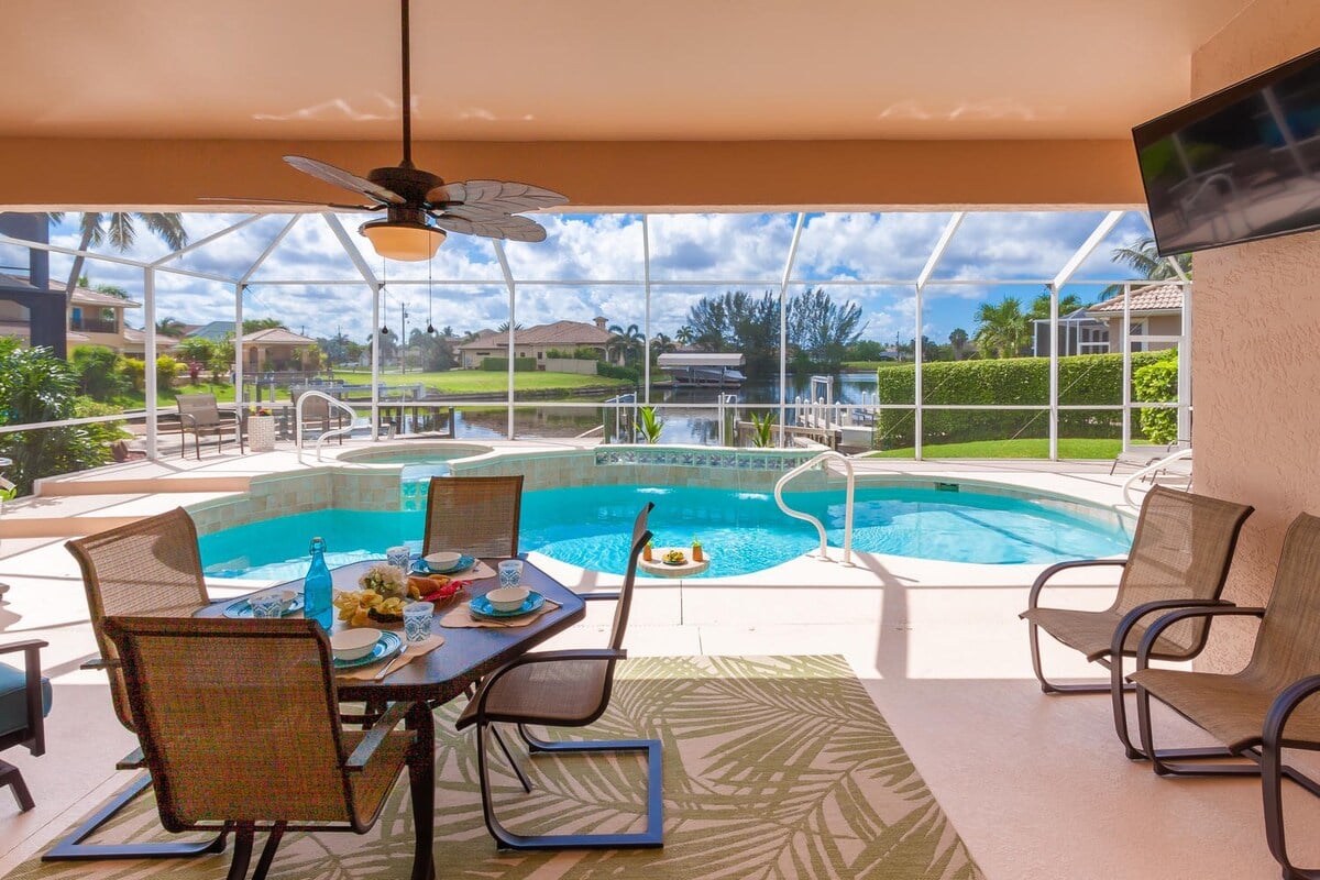 Überdachte Terrasse mit Essbereich und Blick auf Pool und Whirlpool.