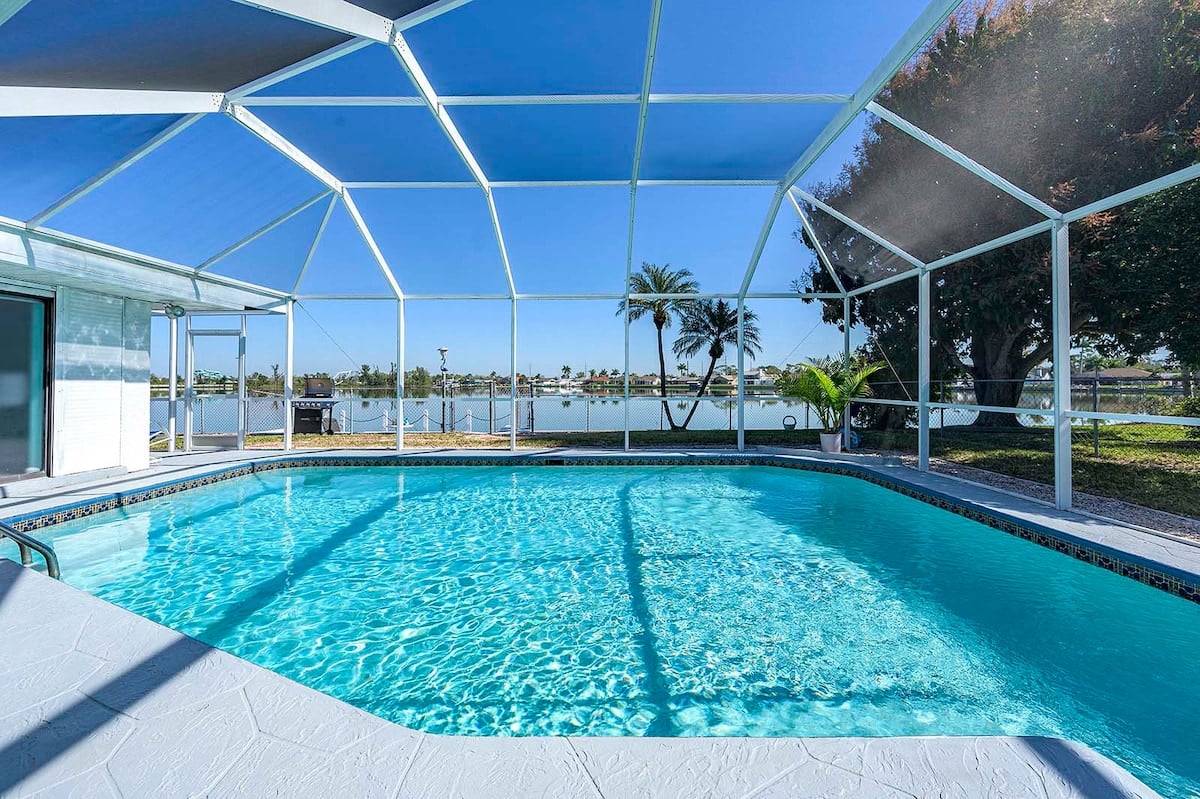 Privater Pool mit Sonnenliegen und Blick auf den See mit Bootsdock.