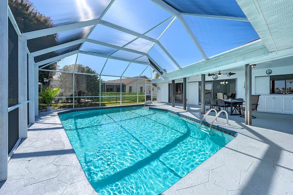 Privater Pool mit Sonnenliegen und Blick auf den See.