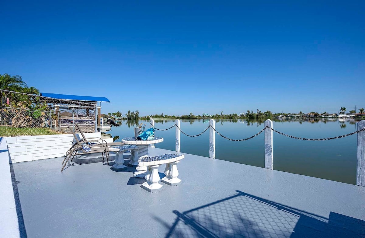 Privater Pool mit Sonnenliegen und Blick auf den See.