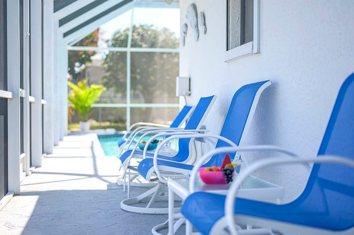 Privater Pool mit Sonnenliegen und Blick auf den See mit Bootsdock.