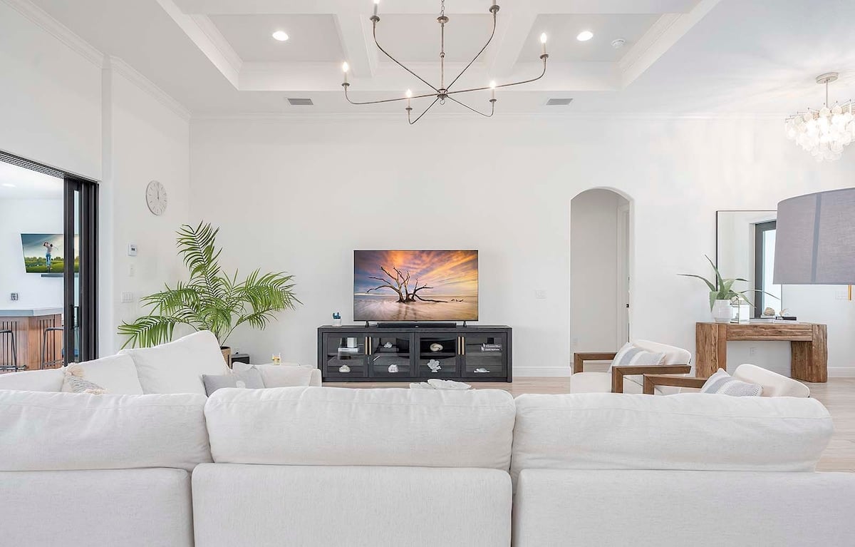 Überdachte Terrasse mit Esstisch und Blick auf Pool und Kanal.