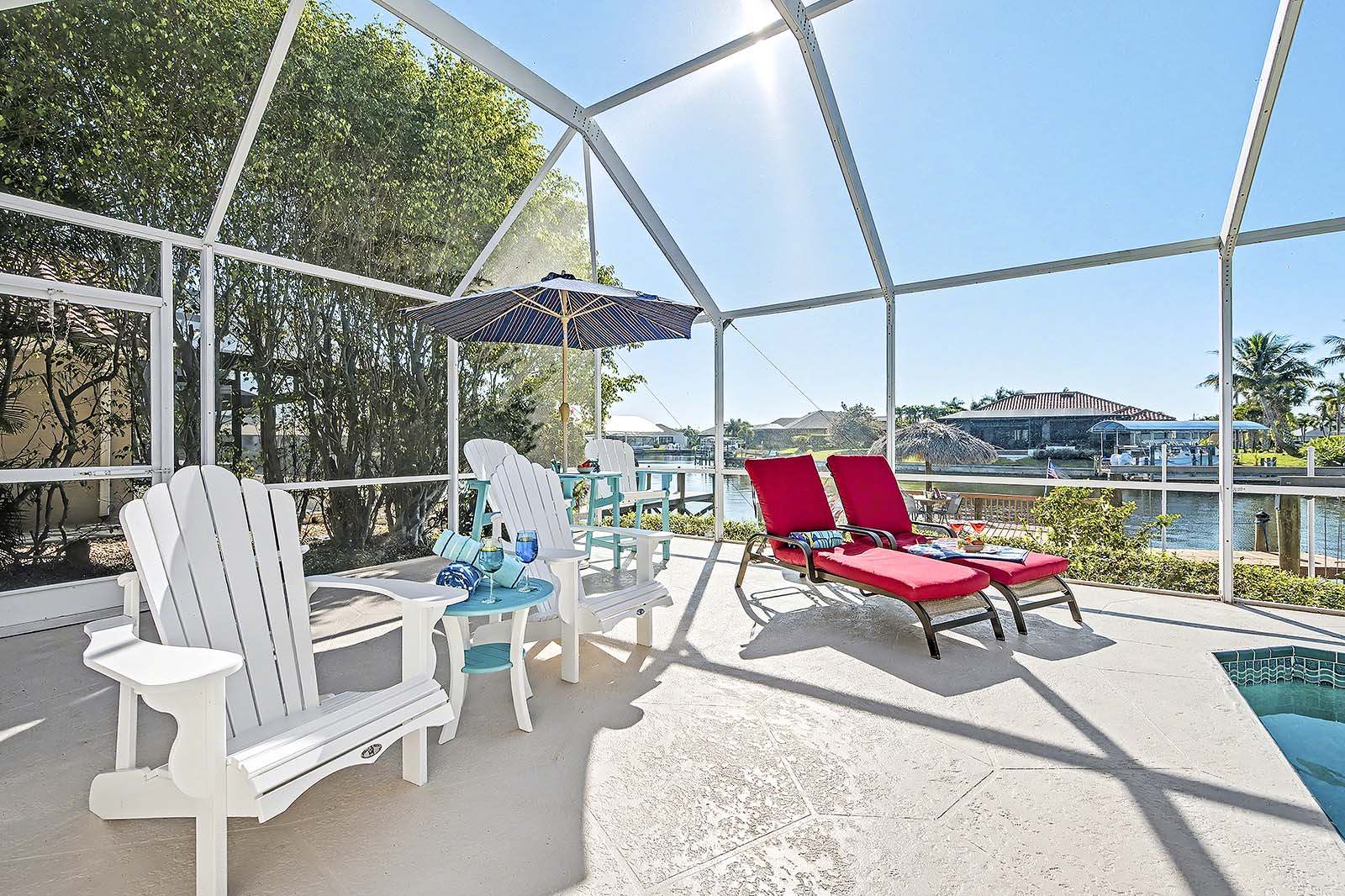 Sonnige Poolterrasse mit Blick auf den Kanal und privatem Bootsdock mit Tiki-Hut.