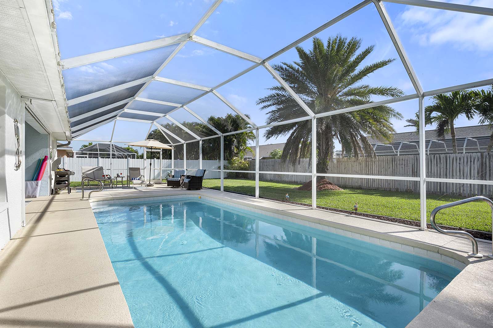 Privater Pool mit Sonnenliegen und Terrasse im eingezäunten Garten.