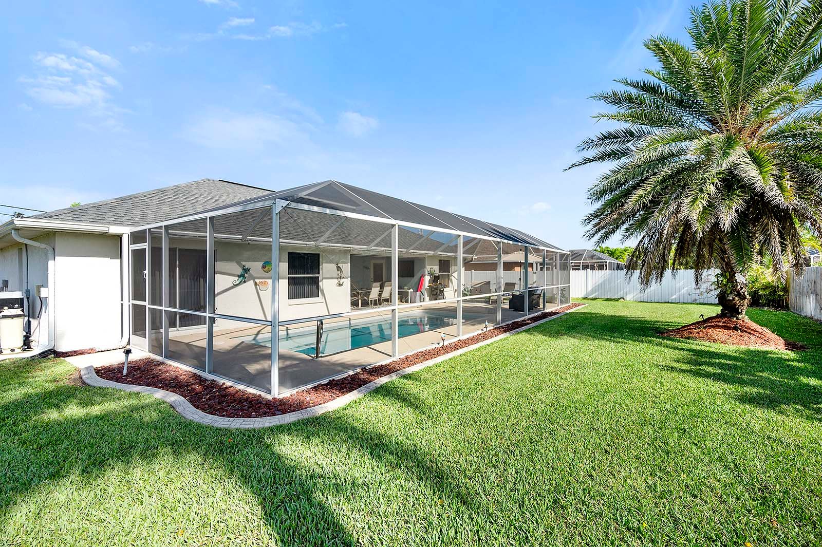 Privater Pool mit Sonnenliegen und eingezäuntem Garten.